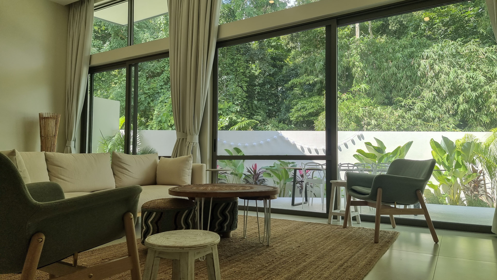 Bright open-plan living room at Pool Villa Lamai with floor-to-ceiling windows overlooking tropical garden